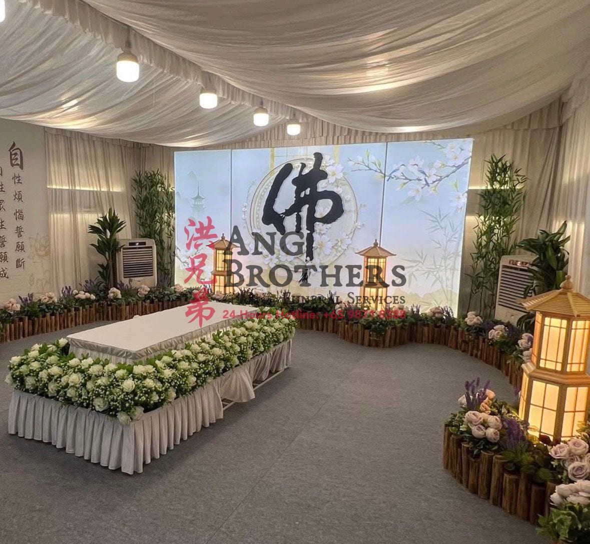 White casket beneath a Buddha backdrop with paper lanterns and white florals