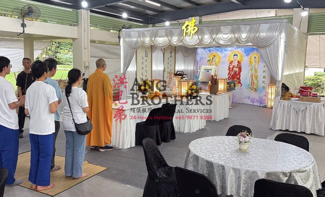 A monk and family gathered before a Buddhist altar, cared for by Ang Brothers