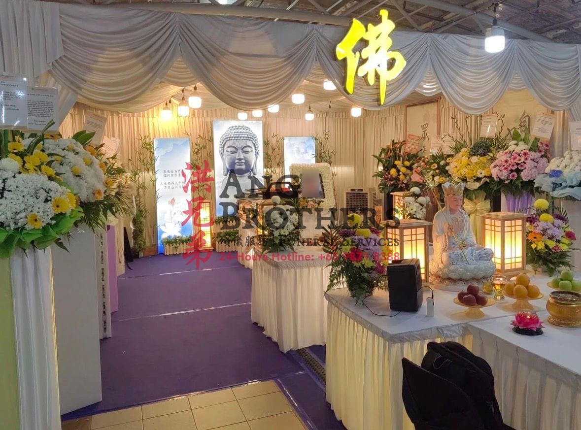 A Buddhist wake with a seated Guanyin, wreaths and offerings beneath the Buddha