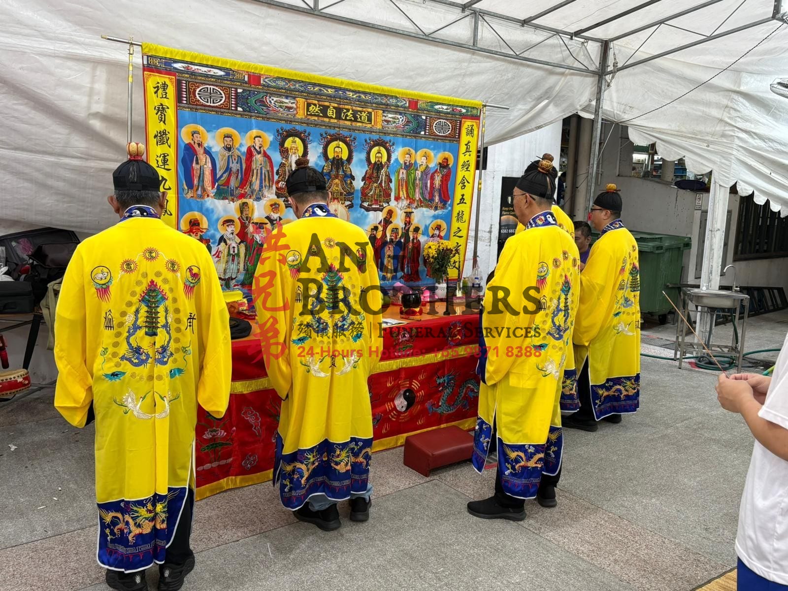 Five Taoist priests in dragon robes leading the chanting before the deity scrolls